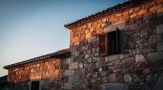 Fachada de piedra tradicional española con luz cálida del atardecer que sugiere el equilibrio térmico entre el día y la noche