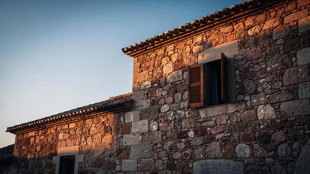 Fachada de piedra tradicional española con luz cálida del atardecer que sugiere el equilibrio térmico entre el día y la noche