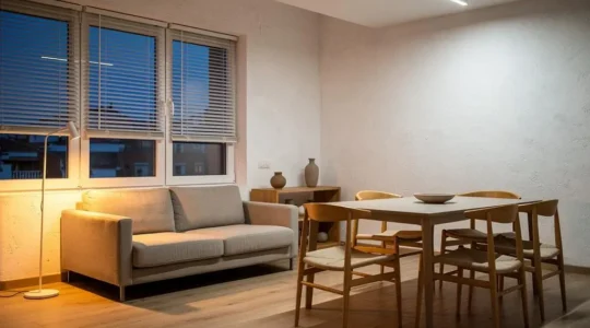 Salón de un piso español moderno iluminado con distintas tonalidades de luz cálida y neutra al atardecer