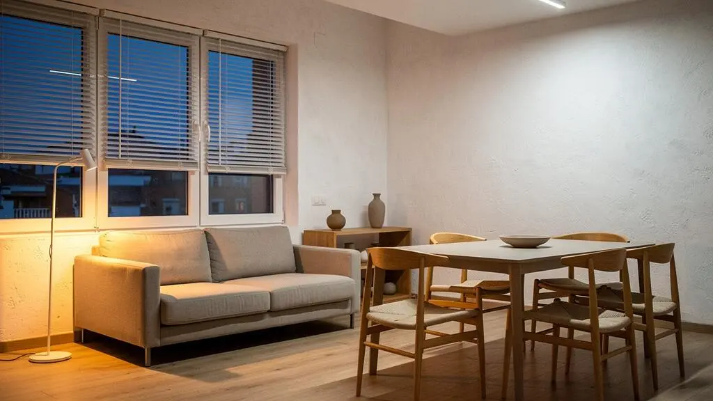 Salón de un piso español moderno iluminado con distintas tonalidades de luz cálida y neutra al atardecer