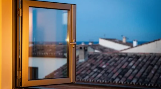 Ventana moderna de aluminio con rotura de puente térmico en una vivienda española, con luz cálida interior y frío exterior contrastados